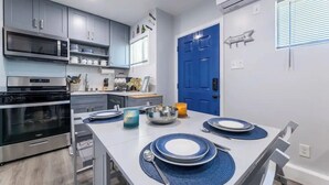 Een moderne keuken met grijze kastjes, roestvrijstalen apparatuur en een blauwe deur.