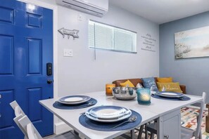 A dining area with a blue door, a white table set with plates, bowls, and candles, and a wall with motivational quotes.