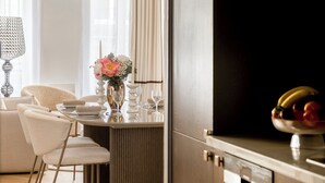Una cocina moderna con un refrigerador oscuro, una mesa de comedor de madera con sillas y una araña.