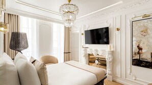 Un dormitorio lujoso con una cama grande, un candelabro, un televisor de pantalla plana y una chimenea.