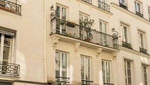 Un edificio de varios pisos con balcones, un café llamado "Cinette Garde Cafe" en la planta baja y un escaparate visible con un letrero.