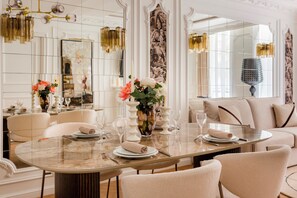 A dining area with a round table, chairs, and a vase of flowers. - Merveil - Luxury Suite - Louvre - Aboukir IX (Paris)