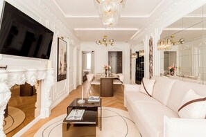 Un salón amplio con una televisión de pantalla plana grande, una chimenea, un candelabro y un sofá.
