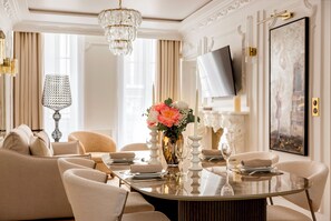 Un comedor formal con una mesa redonda dispuesta para cuatro personas, sillas elegantes, un candelabro y un cuadro grande en la pared.