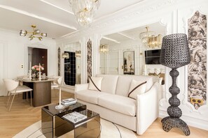 A spacious living room with a white sofa, a glass coffee table, and a decorative floor lamp.