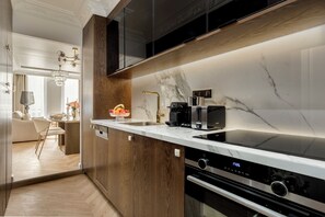Una cocina moderna con encimera de mármol, horno empotrado y cafetera.