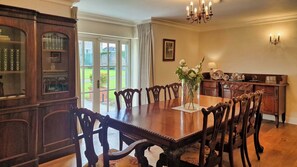 A dining room with a large wooden table, ornate chairs, a chandelier, and a view of the outdoors. - Stunning 5-Bed Period Home,  Gardens & Tennis Court (Malahide)