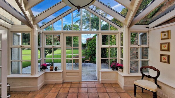 A conservatory with multiple glass doors leading to a garden.