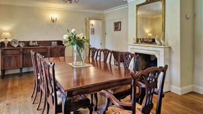 A formal dining room with a large wooden table, ornate chairs, a vase of flowers, a fireplace, and a mirror. - Stunning 5-Bed Period Home,  Gardens & Tennis Court (Malahide)