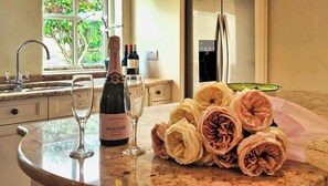 A kitchen counter with a bottle of champagne, two glasses, and a bouquet of roses.