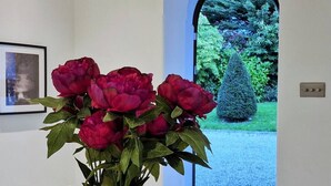 Un vase avec des fleurs rouges est posé sur une table dans un couloir.