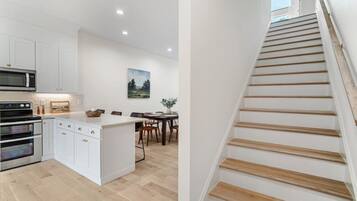 A modern kitchen with white cabinetry, a central island, and a dining area with wooden chairs.