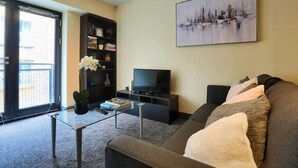 A living room with a sofa, a coffee table, a bookshelf, and a television. - Lovely One Bed Apartment in Hip End of Temple Bar (Dublin 8)