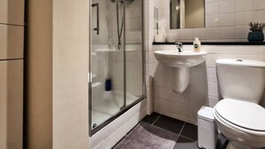 A modern bathroom with a glass-enclosed shower, a sink, and a toilet. - Lovely One Bed Apartment in Hip End of Temple Bar (Dublin 8)