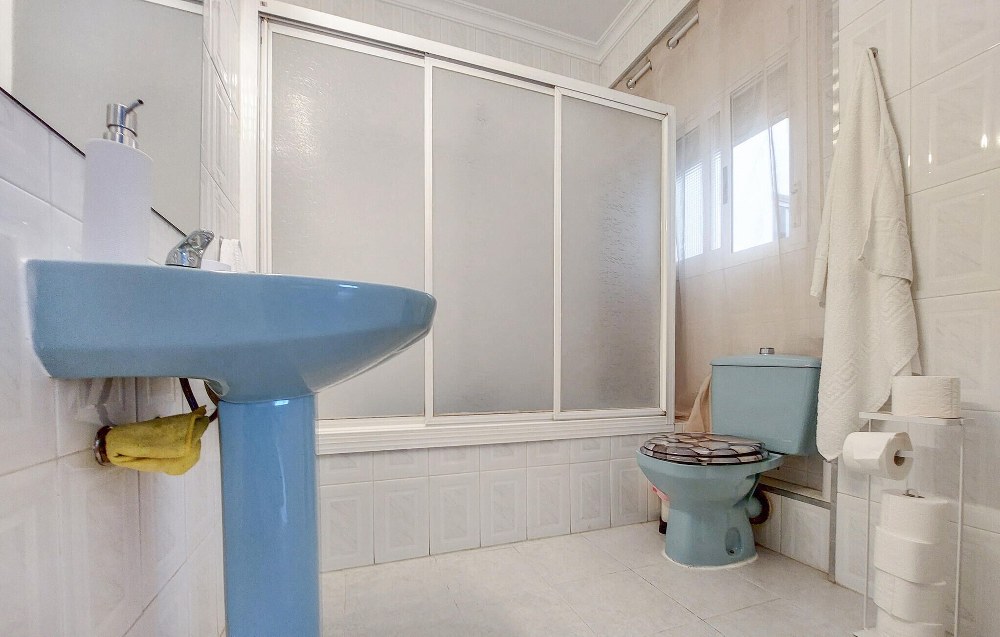 Une salle de bain avec un lavabo bleu, des toilettes et un espace douche.