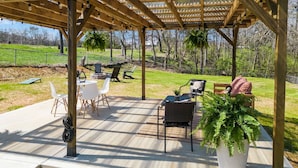 Un patio couvert aménagé avec du mobilier d’extérieur, notamment des chaises et une table, ainsi qu’une plante en pot.