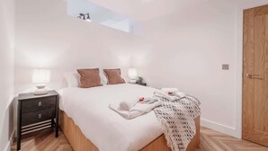 A bedroom with a bed, bedside tables, a nightstand, a wooden door, and a skylight. - Lovely Apartment in Chester Centre (Chester)