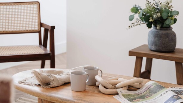 A wooden table with two mugs, a woven placemat, and a newspaper. - Charming Flat in Chester City Centre (Chester)