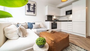 A modern apartment with a living area, kitchenette, and a sofa with cushions. - Central Chester: Cozy and Modern Flat (Chester)