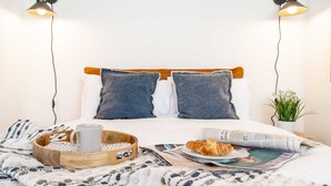 A neatly made bed with pillows, a tray with a mug, a plate with food, and a newspaper. - Central Chester: Cozy and Modern Flat (Chester)