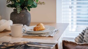 Een tafel met een croissant, een mok en een krant.