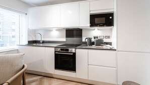 Een moderne keuken met witte kastjes, een Bosch magnetron, een inbouwoven en een koffiezetapparaat.