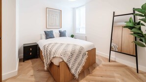 Een slaapkamer met een bed, nachtkastje, en een plant.