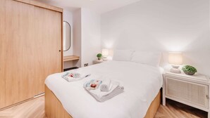 Une chambre d’hôtel avec un lit, une armoire en bois, une table de chevet avec une lampe et une petite plante.