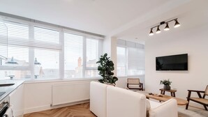 Un salon moderne avec un canapé, une table à manger et un téléviseur fixé au mur.