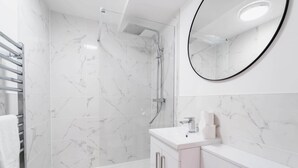 A modern bathroom with a shower, a sink, and a mirror. - Stylish Chester City Apartment (Chester)