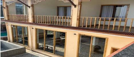 Un edificio a due piani con un balcone, ampie finestre e un patio piastrellato.