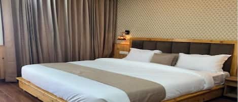 A bedroom with a wooden bed frame, white bedding, and a patterned wall.