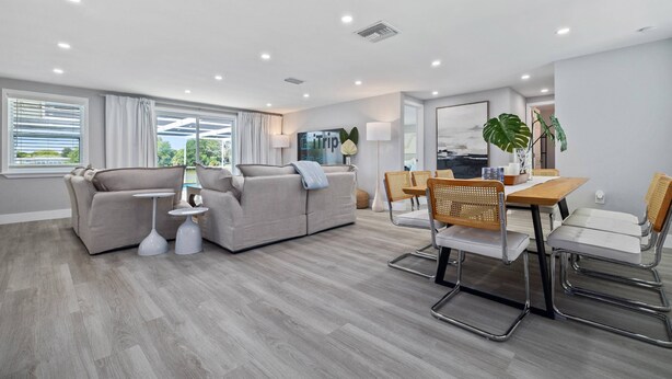 A modern living room with a sofa, dining table, chairs, and a coffee table. - Luxury 3BR Home w/ Heated Pool, Outdoor TV, Bikes & BBQ – Perfect for Families with Modern Kitchen! (Port Richey)