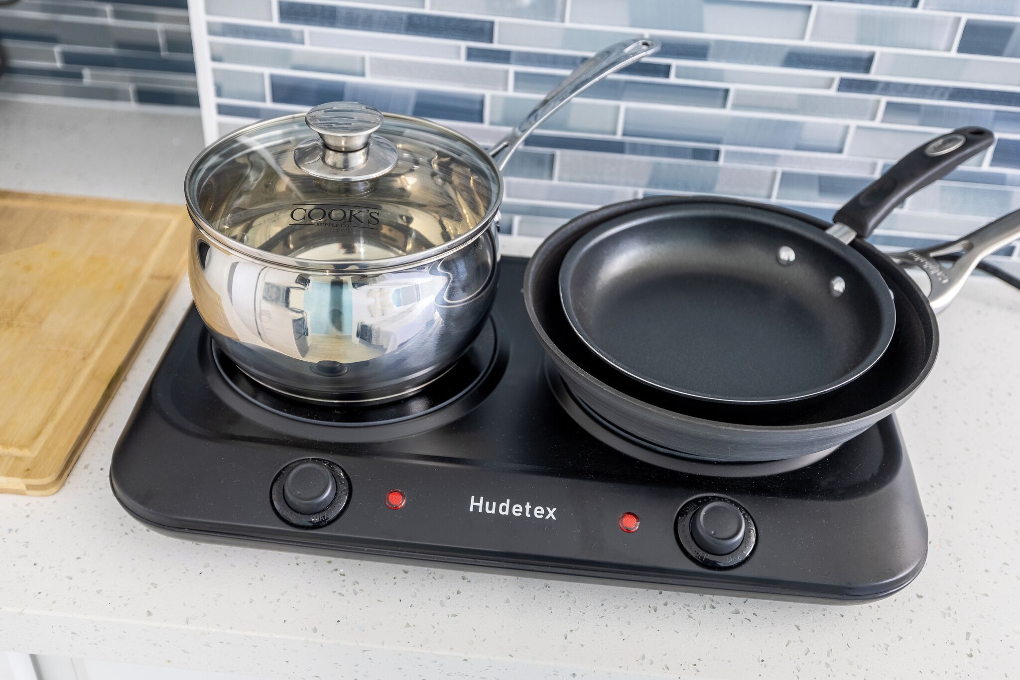 A portable electric stove with a pot and a frying pan on it.