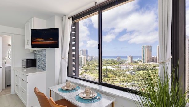 Una cocina moderna con un ventanal grande, un televisor de pantalla plana y un comedor con una mesa lista para dos.