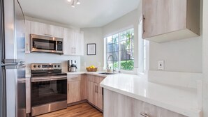 Een moderne keuken met roestvrijstalen apparatuur, houten keukenkastjes en een groot raam voor veel daglicht.