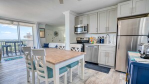 A modern kitchen with white cabinets, stainless steel appliances, and a wooden dining table with chairs.