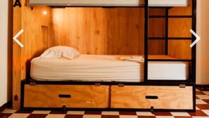 Een stapelbed met houten afwerking en een matras op het onderste bed.