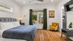 Une chambre à coucher avec un lit, une chaise, un téléviseur et un ventilateur de plafond.