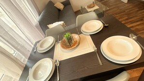A dining area with a glass table, dark wood flooring, and a gray sofa. - Stadtnahe Wohnung mit Küche - Ideal für Familien, Singles und Geschäftsreisende! (Oelde)