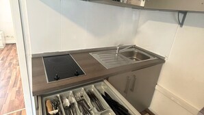 A compact kitchen with a built-in stove, a sink, and a utensil drawer. - Stadtnahe Wohnung mit Küche - Ideal für Familien, Singles und Geschäftsreisende! (Oelde)