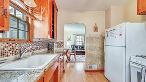 A kitchen with wooden cabinets, a white refrigerator, and a tiled backsplash.