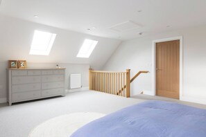 A bedroom with a bed, dresser, and two skylights. - Luxury Chichester Home for 12 (West Sussex)