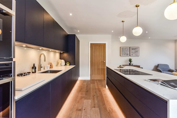 A modern kitchen with dark cabinetry, a central island, and pendant lighting.