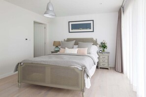 A bedroom with a bed, bedside table, lamp, and a framed picture on the wall.