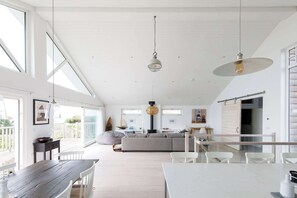 A spacious living area with a large sofa, a dining table, and a kitchen in the background.