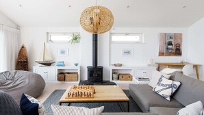 Una sala de estar acogedora con chimenea, un tablero de ajedrez y una lámpara de fibra trenzada grande.