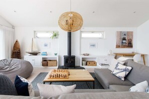 Een gezellige woonkamer met een open haard, een schaakbord en een grote geweven lamp.