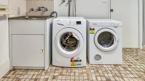 A laundry room with two front-loading washing machines and a sink. - Glenmore Lodge - CBD Location, Hidden Gem (Dubbo)