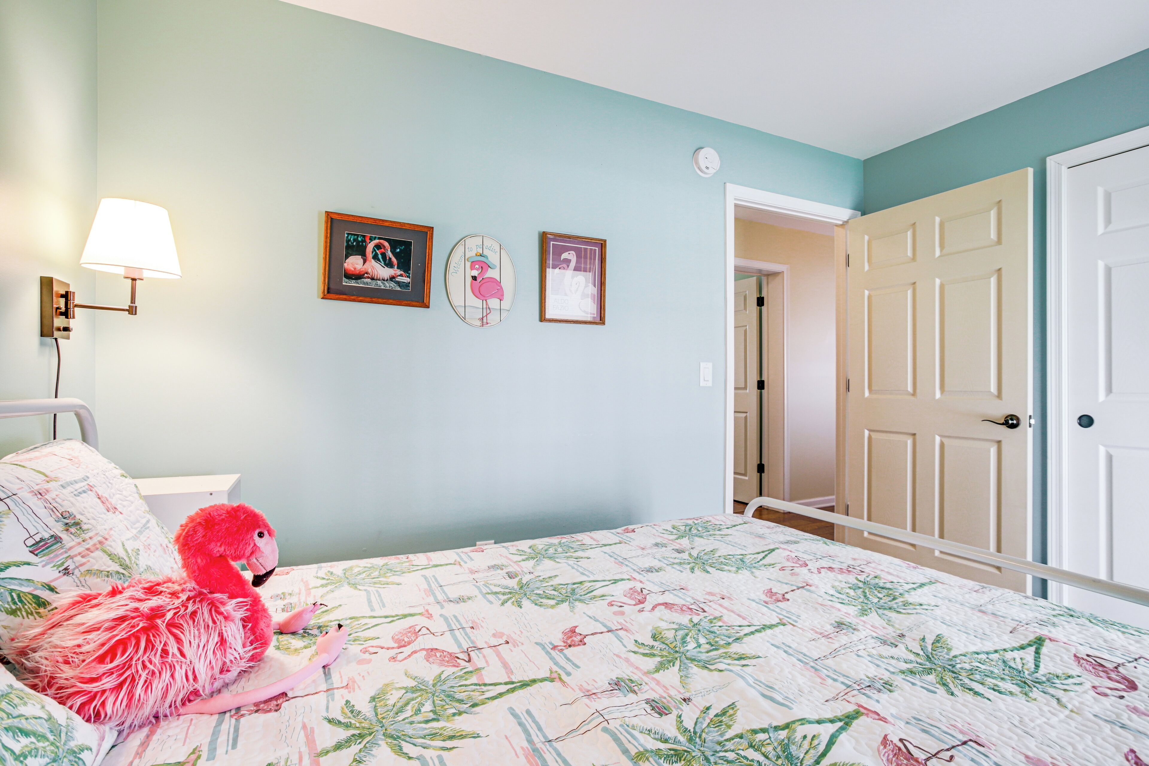 Une chambre à coucher avec un lit, une lampe fixée au mur et des tableaux encadrés.